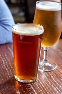 Pint glasses of cold fresh british ale and lager beer served in old vintage English pub