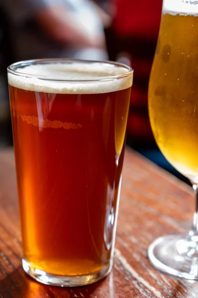 Pint glasses of cold fresh british ale and lager beer served in old vintage English pub