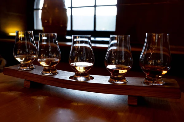 Flight of single malt scotch whisky in glasses served in bar in Edinburgh, UK, tasting of dram of whiskey