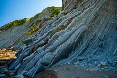 Zumaia 'nın Atlantik kıyısındaki alçak gelgitte, İspanya' nın Bask Bölgesi 'nde dik eğimli sinek jeolojik oluşumuna bakın.