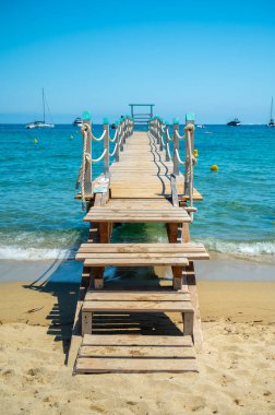 Saint-Tropez yakınlarındaki efsanevi Pampelonne plajındaki yatların misafirleri için ahşap iskele. Fransız Riviera, Fransa 'nın beyaz kumlu sahillerinde yaz tatili.