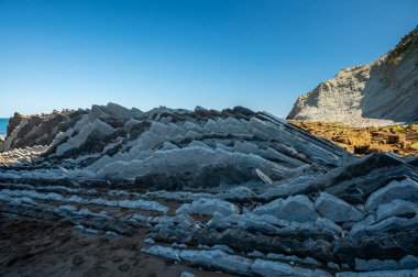 Zumaia 'nın Atlantik kıyısındaki alçak gelgitte, İspanya' nın Bask Bölgesi 'nde dik eğimli sinek jeolojik oluşumuna bakın.