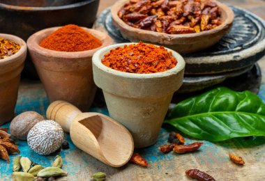 Renkli zemin baharatlı kırmızı biber, pimento ve curcuma ahşap masaya yakın kil çömlekler.