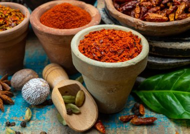 Renkli zemin baharatlı kırmızı biber, pimento ve curcuma ahşap masaya yakın kil çömlekler.