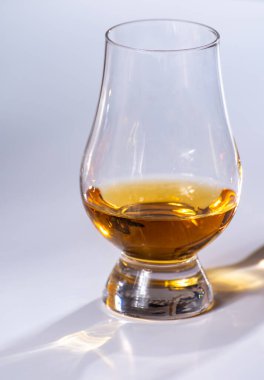 Lale şeklindeki tadım bardağı, bir dirhem İskoç viskisi ya da beyaz arka planda harmanlanmış viskiyle yakın plan.