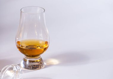 Lale şeklindeki tadım bardağı, bir dirhem İskoç viskisi ya da beyaz arka planda harmanlanmış viskiyle yakın plan.