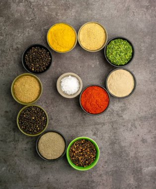 Koyu arka planda yemek pişirmek için dramatik bir konsepte sahip çeşitli baharatların yüksek kaliteli yakın plan fotoğrafı..