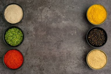 Koyu arka planda yemek pişirmek için dramatik bir konsepte sahip çeşitli baharatların yüksek kaliteli yakın plan fotoğrafı..