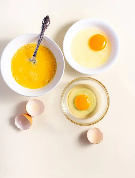 Egg beat, Egg Shell. Raw eggs in a glass and white bowl on the table. Flat lay. Broken White Background.