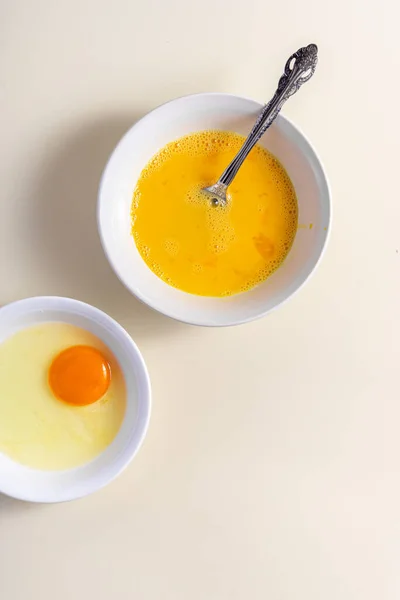 Egg beat, Egg Shell. Raw eggs in a glass and white bowl on the table. Flat lay. Broken White Background.
