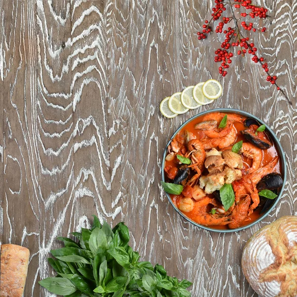 Seafood in tomato sauce with herbs. Shrimps, mussels, crayfish in red sauce on a wooden table, bread, herbs, herbs. Italian food. Background for the menu. View from above