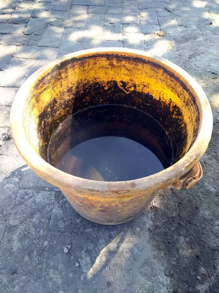 Beton zeminde paslı metal tencere.