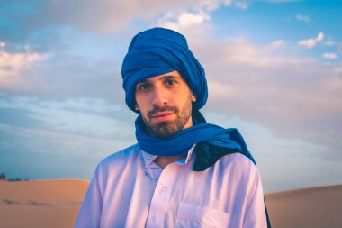 Şafak vakti Sahra Çölü 'nde geleneksel Tuareg giysileri giyen Berber adam, Merzouga, Fas