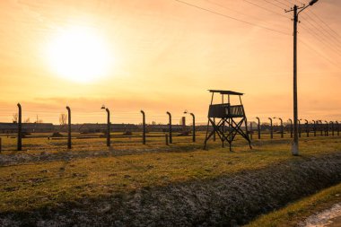 AUSCHWITZ BIRKENAU. POLAND, 9 HAZİRAN 2022: Günbatımında Auschwitz II Birkenau Nazi İmha Kampı 'nda nöbet kulesi