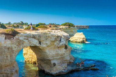 SALENTO, İtalya, 11 AĞUSTOS 2021: Apulia 'nın güzel kristal berraklığı kayalıklardan ve Sant' Andrea 'nın deniz yığınlarından