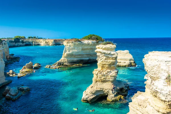 SALENTO, İtalya, 11 AĞUSTOS 2021: Apulia 'nın güzel kristal berraklığı kayalıklardan ve Sant' Andrea 'nın deniz yığınlarından