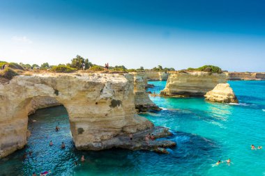 SALENTO, İtalya, 11 AĞUSTOS 2021: Apulia 'nın güzel kristal berraklığı kayalıklardan ve Sant' Andrea 'nın deniz yığınlarından