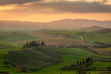 Sunrise over a lone farm in the middle of the hills of the Tuscany countryside, Italy