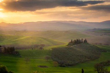 Sunrise over a lone farm in the middle of the hills of the Tuscany countryside, Italy