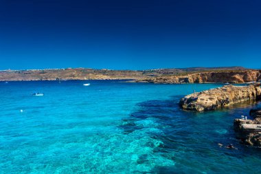 Comino, Malta, 22 May 2022: Tourists swimming in the crystal clear water of the Blue Lagoon