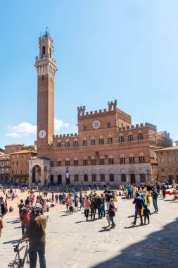Siena, İtalya, 17 Nisan 2022: Turistler Piazza del Campo meydanının ve İtalya 'nın Siena kentindeki belediye binasının keyfini çıkarıyorlar. Siena 'nın tarihi merkezi UNESCO tarafından Dünya Mirası Alanı ilan edildi..
