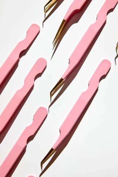 Herramientas para el procedimiento de extensión de pestañas. Patrón de pinzas de color rosa en la placa de mármol. Sobre fondo blanco. Concepto de belleza y moda — Foto de Stock