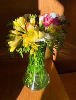 Beautiful bouquet of flowers in a vase on a white wooden background in the interior