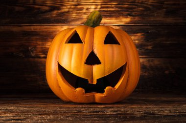 Jack Lantern veya Jack-o 'Lantern Cadılar Bayramı balkabağı. Seramik dekorasyon, ürkütücü kahkahalar, ahşap arka planda korkunç kafa..