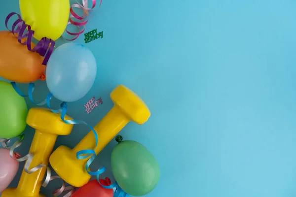 Zwei Gelbe Hanteln Bunte Luftballons Und Bänder Fitnessgeräte Als Geschenk — Stockfoto