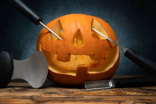 Halloween pumpkin carving tools spoon gutter and saw blades, with carved Jack Lantern (Jack-o\'-lantern) spooky laughing, scary head.