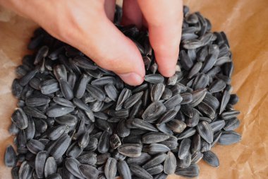 Ayçiçeği tohumları kağıda konur, yakın çekim. Adam biraz tohum toplamak istiyor..