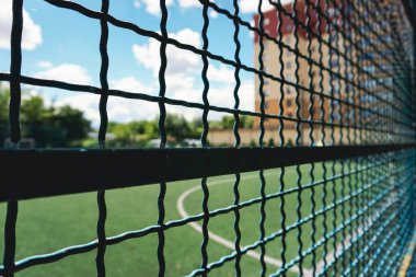 A field for playing football, behind a metal fence.