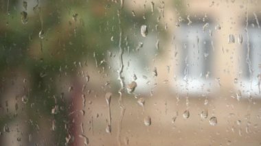 Bardaktan aşağı yağmur damlaları akıyor. Pencereye yakın planda yağmur damlaları düşer. Pencereden bak. Yağmurlu bir gün. Cama düşen su damlalarının yakın görüntüsü.