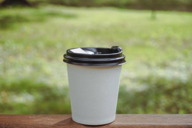 Bir fincan kahve. Çay ya da kahve ile beyaz kağıt bardak. Arka planda bir fincan kahve. Güneşli bir gün. Sıcak içecekler için beyaz kağıt bardak..