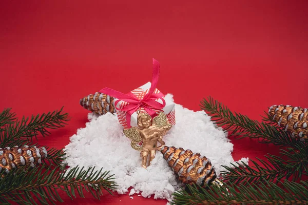 A small Christmas box on a red background. Christmas box in the snow.