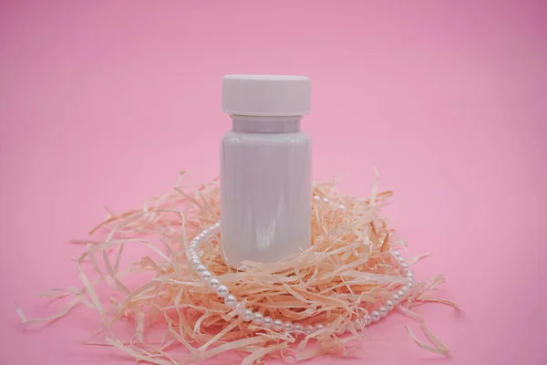 White supplement bottle for medicine, on a pink background. White bottle.