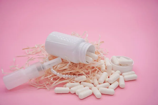 Bottles with medicine, nasal spray. White capsules on a pink background.