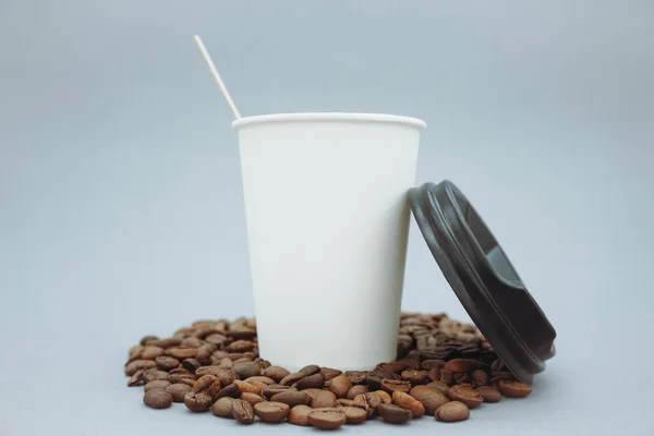 Paper cup and plastic lid mockup or mock up template. Coffee beans and a cup on a gray background.