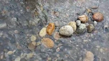 Nehirler, su, göller, kayalar ve doğa temalı video veya çekim projelerinize uygun temiz ve yumuşak bir nehir akışının kenarındaki taşların düzenlenmesi