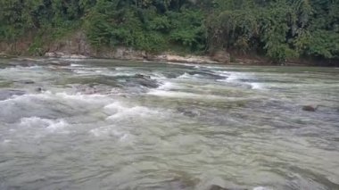 Akıp giden nehir kayalıkların arasından akar tıpkı dans eder gibi nehirler, su, göller ve doğa temalı video veya çekim projeleriniz için uygun bir şekilde.