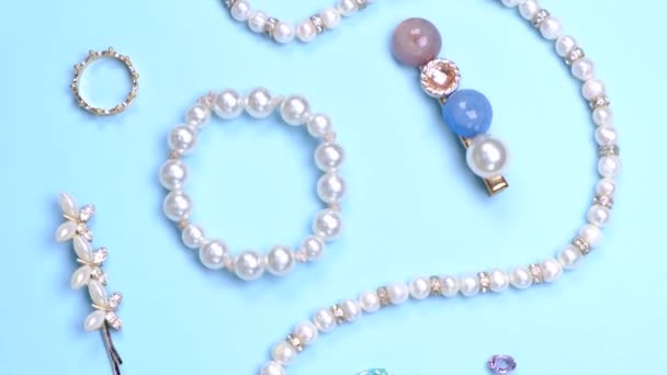 蓝色背景上有珍珠 发夹和宝石的珠宝的扁平组合 高质量的4K镜头 — 图库视频影像