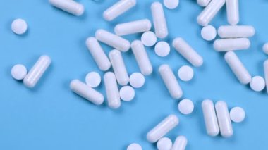 Beyaz haplar ve kapsüller, mavi zemin üzerinde ilaçlar, farmakoloji, ilaç veya tedavi kavramı, metin eklemek için bir şablon,