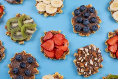 Arkaplanda çikolata serpiştirilmiş, fındık ve meyveli tatlı gofretlerin arka planı. Yaz, aydınlık, modaya uygun arka plan, yemek tasarımı. Yüksek kalite 4k görüntü