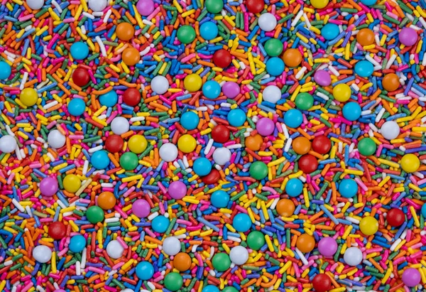 background of multi-colored sprinkles for sweets and multi-colored dragees or sweets. The concept of celebrating a birthday, party or other holidays. trendy, sweet background.