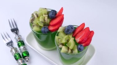 İki meyve jöleli tatlı bardakta kivi çileği ve yabanmersinli yakın plan beyaz arka plan..