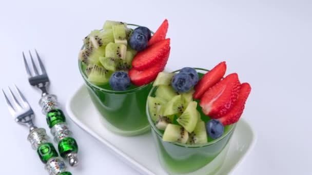 Δύο Ζελέ Φρούτων Πράσινα Επιδόρπια Ποτήρια Φράουλες Ακτινίδιο Και Βατόμουρα — Αρχείο Βίντεο