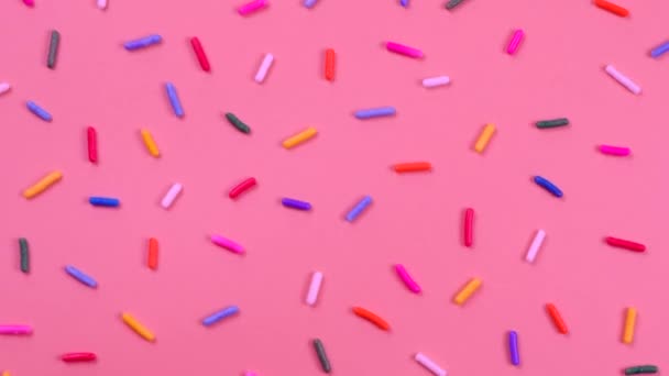 ピンクの背景にお菓子のためのスプリンクルの回転の背景誕生日 パーティーや他の休日を祝うという概念 高品質4K映像 — ストック動画