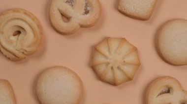 Bej ya da şeftali arka planda dönen kurabiyelerin arkaplanı, pastel renklerde yemek modasına uygun arka plan. Yüksek kalite 4k görüntü