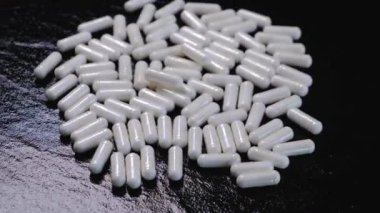 Siyah arka planda dönen beyaz kapsüller ya da tabletler. Yüksek kalite 4k görüntü