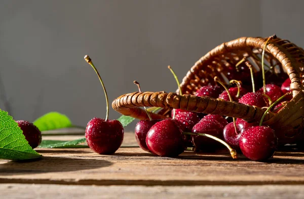 Olgun kirazlar küçük bir sepetin içinde, ahşap bir masanın üzerinde.. 